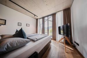 a bedroom with a large bed and a tv at Boutique-Hotel LARTOR in Unterammergau