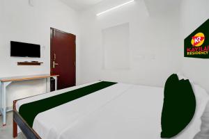 a bedroom with a white bed and a tv at Kayilai Residency in Pīlamedu