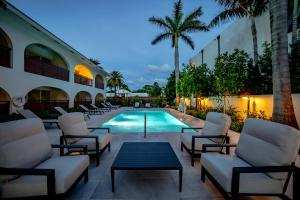 a swimming pool with chairs and a table next to a building at The Mizner - 2BR Waterfront Boca Suite in Boca Raton