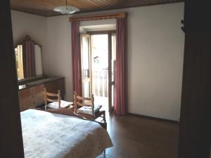 a bedroom with a bed and a mirror and a window at Appartamenti Kratter Valeria in Sappada