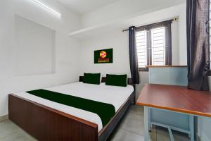 a small bedroom with a bed and a desk at Kayilai Residency in Pīlamedu