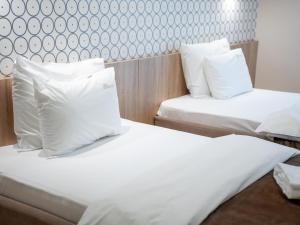 two beds in a hotel room with white pillows at Garni Hotel Mlinarev san in Arilje +33 photos