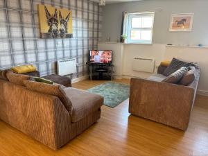 a living room with two couches and a television at Quiet cottage, Ryan Anglesey in Holyhead
