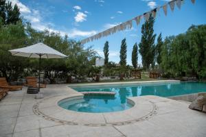 a large swimming pool with an umbrella and chairs at Abismo Privado Cabaña de Lujo con Jacuzzi in San Rafael