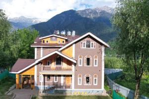 a large house with mountains in the background at The Forest Castle Resort in Pahalgām