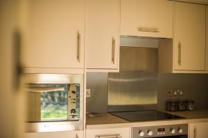 a kitchen with white cabinets and a microwave at Heathend in Petworth