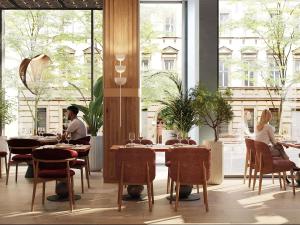 a restaurant with people sitting at tables in a room with large windows at Mövenpick Yerevan in Yerevan