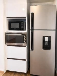 a stainless steel refrigerator next to a microwave at Casa Corferias in Bogotá