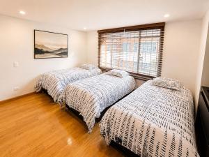two beds in a room with a window at Casa Corferias in Bogotá +13 photos