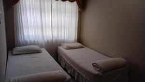 two beds in a small room with a window at Jack & Ace in Durban
