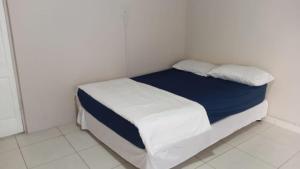 a small white room with a bed with blue sheets and pillows at Jack & Ace in Durban
