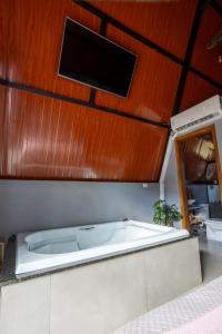 a bath tub in a room with a tv on the ceiling at Chalé Aliança in Poços de Caldas