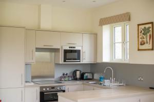 a kitchen with white cabinets and a sink and a microwave at Highfield in Petworth