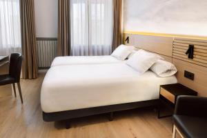 a hotel room with two beds and a desk at Hospedium Hotel Lleida in Graus