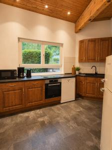 a kitchen with wooden cabinets and a black and white dishwasher at Bachchalet im Schwarzwald in Sasbachwalden