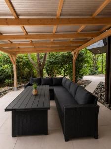 a black couch and a table under a wooden roof at Bachchalet im Schwarzwald in Sasbachwalden