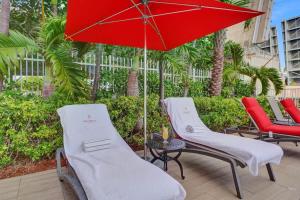 two chairs and a red umbrella on a patio at Charming Studio by the Ocean Beach Service in Hallandale Beach