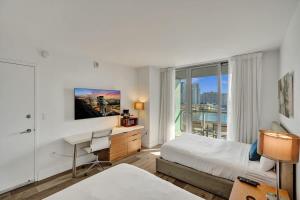 a bedroom with a bed and a desk and a window at Charming Studio by the Ocean Beach Service in Hallandale Beach