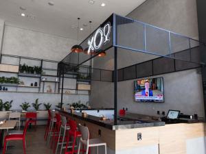 a restaurant with a bar with red chairs and a tv at ibis Araguaína in Araguaína