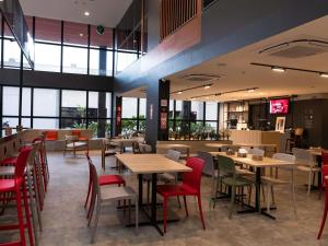 a restaurant with wooden tables and red chairs at ibis Araguaína in Araguaína