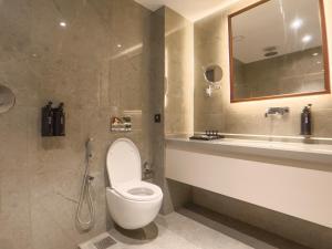 a bathroom with a toilet and a sink and a mirror at Alora Grand Hotel Calicut in Kozhikode