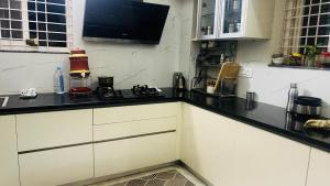 a kitchen with white cabinets and a black counter top at PR PREMIUMSUITs in Surūrnagar
