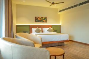 a bedroom with a bed and a couch and a chair at Alora Grand Hotel Calicut in Kozhikode +81 photos