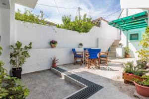 a patio with blue chairs and a white wall at The Hidden Gem Skopelos - Elegant Island Retreat in Skopelos Town