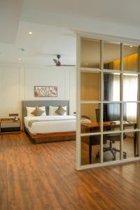 a bedroom with a bed and a desk with a desk at Alora Grand Hotel Calicut in Kozhikode