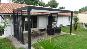 a black pergola with a picnic table in a yard at Pinede in Labenne
