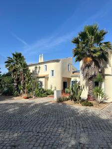 a house with palm trees and a cobblestone driveway at Casa Romeo y Julieta in Castro Marim