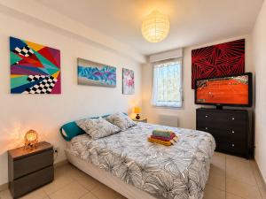 a bedroom with a bed and a flat screen tv at " Régussol Coloré " Piscine - Linge fourni - Wifi in Castelnau-dʼEstrétefonds