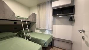 a small room with two beds and a window at Camping Delfino in Albenga