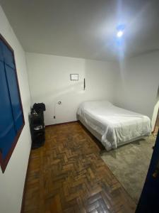 a bedroom with a bed and a wooden floor at Kitnet Imperial in Ouro Preto