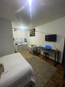 a bedroom with a bed and a desk with a laptop at Kitnet Imperial in Ouro Preto