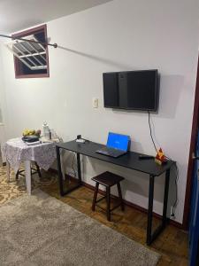 a black desk with a laptop and a tv on a wall at Kitnet Imperial in Ouro Preto
