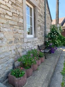 a stone building with a row of flower pots next to a bench at Le Cat'saisons in Wellin