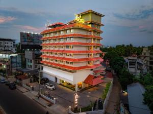 a tall building with a yellow sign on top of it at Alora Grand Hotel Calicut in Kozhikode