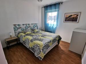 a bedroom with a bed with a comforter and a window at Le Moulin in Saint-Nolff