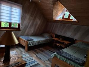a attic room with two beds and a window at Lukin salaš broj 3 in Ratkovo