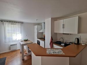 a kitchen with white cabinets and a wooden counter top at Le Moulin in Saint-Nolff
