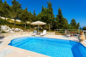 a swimming pool with chairs and an umbrella at Villa Windmill in Vlachopoulátika +6 photos