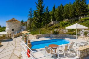 a pool with chairs and an umbrella next to a house at Villa Windmill in Vlachopoulátika