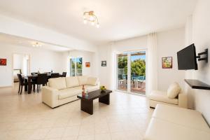 a living room with white furniture and a dining room at Villa Peach in Katelios
