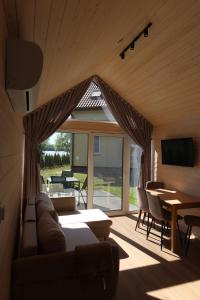 a living room with a couch and a table and a television at Domki Paradise Charzykowy in Charzykowy