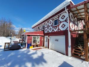 a red and white building with a garage in the snow at Billie's Backpackers Hostel in Fairbanks