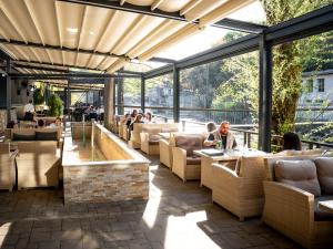a restaurant with couches and tables and windows at Garni Hotel Mlinarev san in Arilje