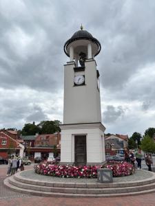 a clock tower with flowers in front of it at Butas pačiame miesto centre in Telšiai