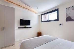 a bedroom with a bed and a tv on the wall at La Maison Solférino in Boulogne-Billancourt