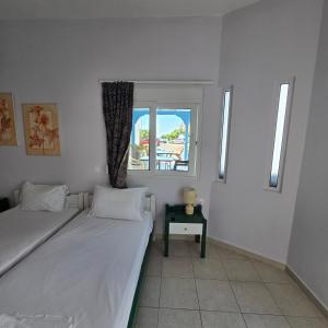 two beds in a room with a window at Soula appartments in Makry Gialos